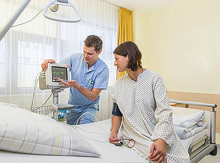 Student steht bei Patientin am Krankenbett
