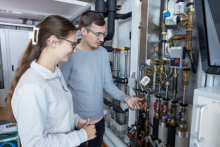 Zwei Green Building Studierende am Wärmpepumpenprüfstand am Campus Kuchl im Labor