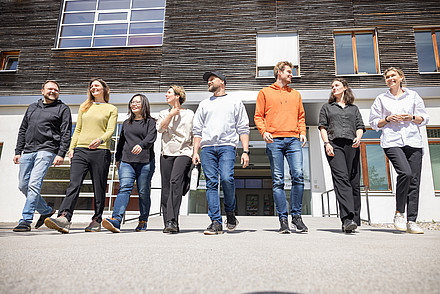 Acht Personen gehen in einer Reihe vom FH-Gebäude weg