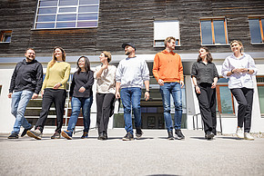 Acht Personen gehen in einer Reihe vom FH-Gebäude weg