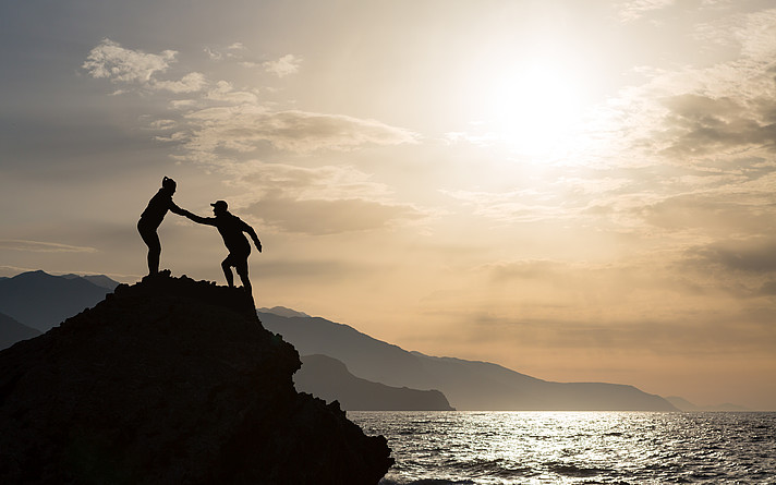 Teamwork couple climbing hiking with helping hand