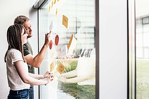 Zwei Studierende vor Glaswand mit post-its