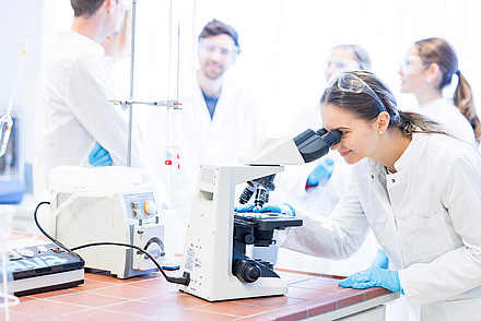 Studentin die in ein Mikroskop schaut im Labor am Campus Kuchl