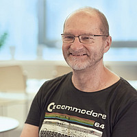 Eine Person sitzt, Stühle und Fenster im Hintergrund