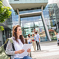 Studentin mit Unterlagen in der Hand sitzt vor dem FH-Gebäude am Campus Urstein