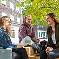Studierende sitzen vor dem Campus Gebäude im Grünen in Kuchl