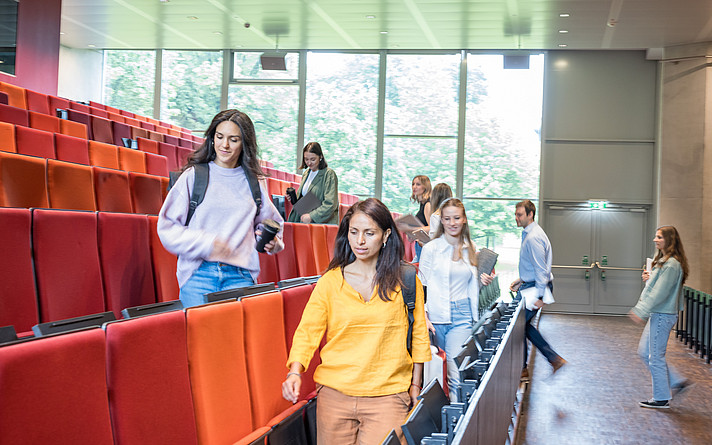 Studentinnen und Studenten gehen in das Audimax am Campus Urstein