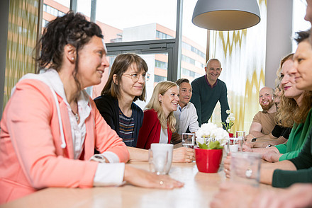 Personengruppe sitzt um einen Tisch und unterhält sich