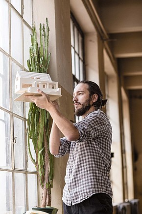 Mann hebt das Modell eines Hauses gegen das Fenster